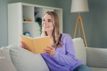 Photo of nice young girl sit couch reading book enjoy cozy wear violet clothes modern cozy interior...