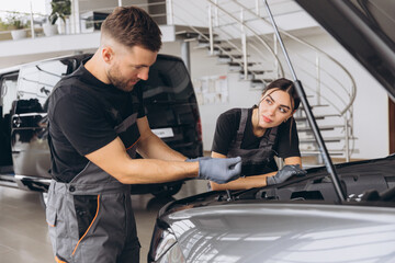 Trying to identify the source of the problem. Two mechanics man and woman working together at open...