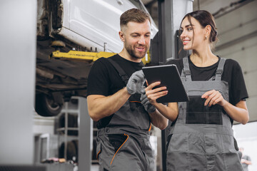 Young expert female inspects repair checklist with automotive mechanic worker partner, quality...