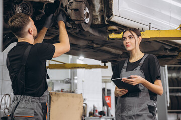 Young expert female inspects repair checklist with automotive mechanic worker partner, quality...