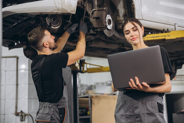 Young expert female inspects repair checklist with automotive mechanic worker partner, quality...