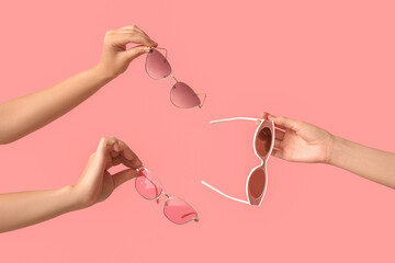 Female hands with different stylish sunglasses on pink background