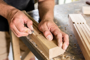 The carpenter grinds the edge of the oak plank with his hands