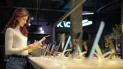 A woman is currently looking at a cell phone while in a store