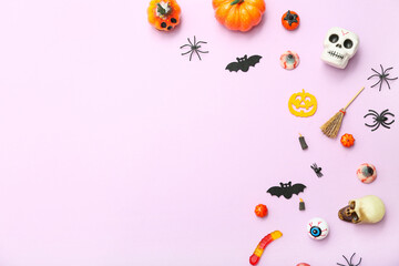 Composition with different decorations and candies for Halloween on lilac background