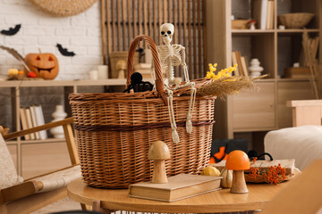 Wicker basket with books and Halloween decor on table in living room