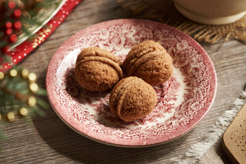 Three homemade Christmas cookies in the form of nuts filled with cocoa cream on a red plate on a table