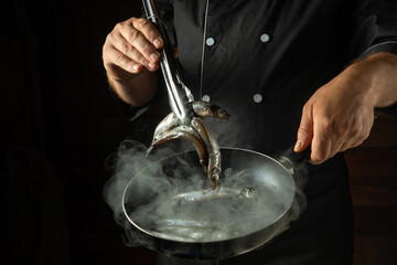 Cooking sprats fish in a frying pan. A chef fries capelin in a restaurant kitchen before dinner....