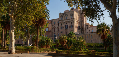 historic Palazzo dei Normanni in Palermo, Sicily, framed by lush gardens and palm trees, the architectural grandeur of Norman Palace amidst peaceful garden environment