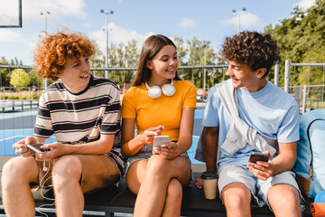 Group of teenagers students high school pupils classmates using gadgets holding smart mobile phones...
