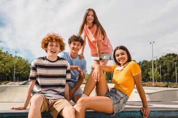 Photo of happy smiling friends teenagers high school pupils college students spending time summer holiday having fun meeting hanging out outside in skate green nature park looking at camera
