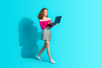 Fototapeta premium Full size photo of nice young girl walk use netbook wear top isolated on teal color background