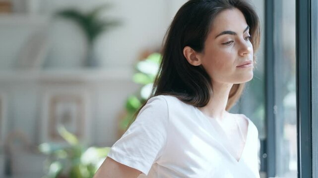 Video of smiling young woman posing while looking at camera in the living room at home.
