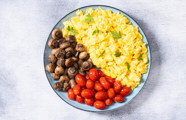 Homemade scrambled eggs with mushrooms and cherry tomatoes