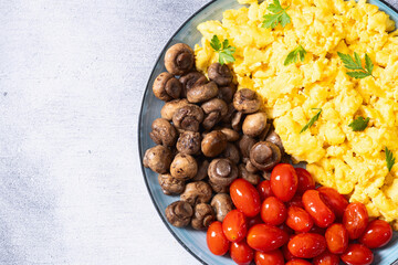 Homemade scrambled eggs with mushrooms and cherry tomatoes