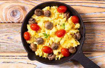 Healthy vegetarian breakfast . Scrambled eggs in pan with cherry tomatoes and parsley
