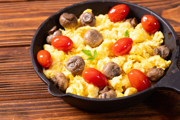 Healthy vegetarian breakfast . Scrambled eggs in pan with cherry tomatoes and parsley