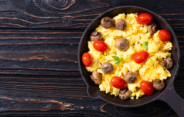 Healthy vegetarian breakfast . Scrambled eggs in pan with cherry tomatoes and parsley