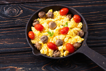 Healthy vegetarian breakfast . Scrambled eggs in pan with cherry tomatoes and parsley