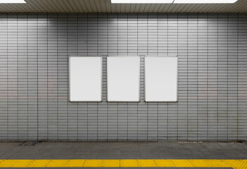 Three blank billboard advertising poster on a subway station platform wall. Space for text for...