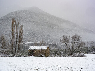 Typical cabin in the snowy Aragonese Pyrenees. Surrounded by fields and snowy mountains.