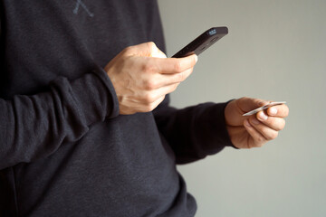Man holds bank card and mobile phone in his hands.
