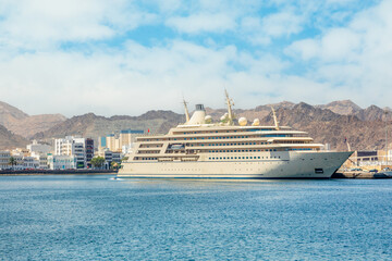 Mutrah promenade panorama with mountains and tourist cruise liner ship anchored in port of Muscat, sultanate Oman