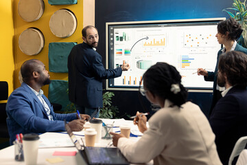 Team of business associates discussing ways to increase revenue in an executive meeting, analyzing statistics to conclude project. Enterprise workers collaborating to achieve goals.