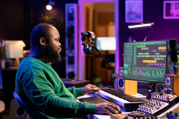 African american composer creating a new track for a project, using professional production pc...