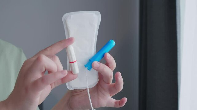 woman hands holding pad and tampon making decision of hygienic products. Different types of feminine menstrual hygiene materials 