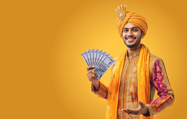 Obraz premium Indian man wearing traditional outfit holding rupee money on his hand on isolated background