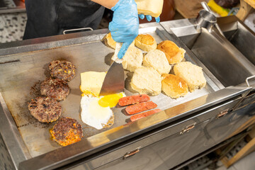 Cook preparing fast food cheeseburgers on a hot griddle