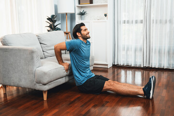 Athletic body and active sporty man using furniture for effective targeting muscle gain exercise at gaiety home exercise as concept of healthy fit body home workout lifestyle.