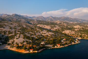 Serene coastal village in Croatia at sunset with hills in the background. 