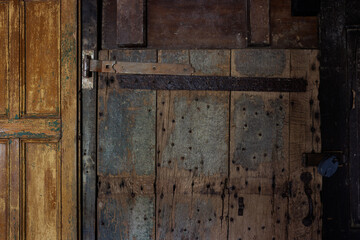 A door with a rusty lock and a wooden frame. The door is old and has a worn appearance