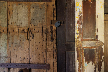 The door is old and has a lock on it. The door is made of wood and has a rustic appearance