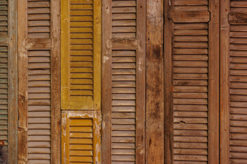 A wooden wall with yellow and brown slats. The slats are arranged in a way that creates a sense of depth and texture. Scene is warm and inviting