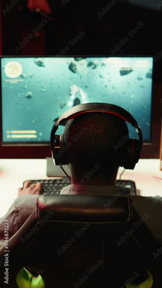Poster vertical video man playing sf videogame on pc screen, shooting asteroids, putting headphones on. clo
