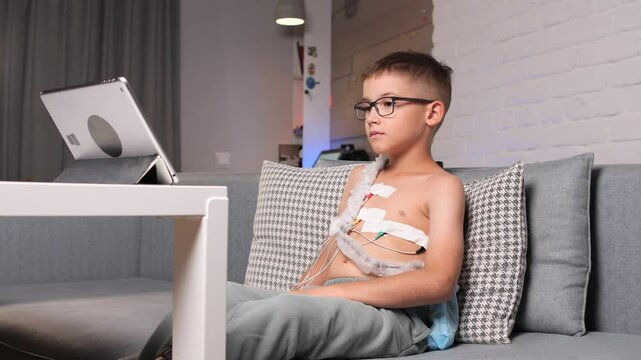 Child patient wearing ekg holter monitor watching tablet