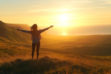 Fototapeta premium Woman with Outstretched Arms Standing on a Grassy Hill Overlooking the Ocean at Sunrise, Bathed in Warm Golden Light, Capturing a Serene and Joyful Moment of Freedom and Nature's Beauty