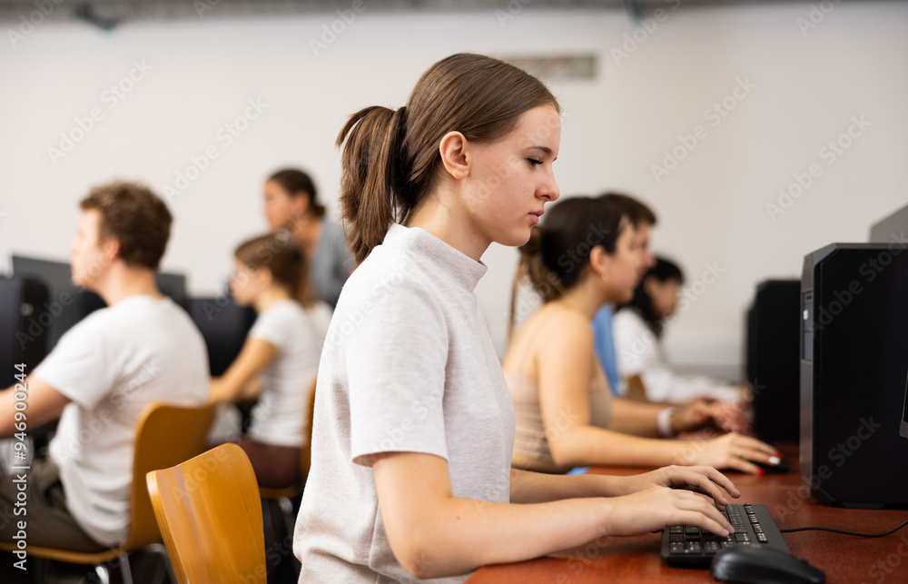 Poster smart female teenager learning computer science while she is using a pc in the computer classroom