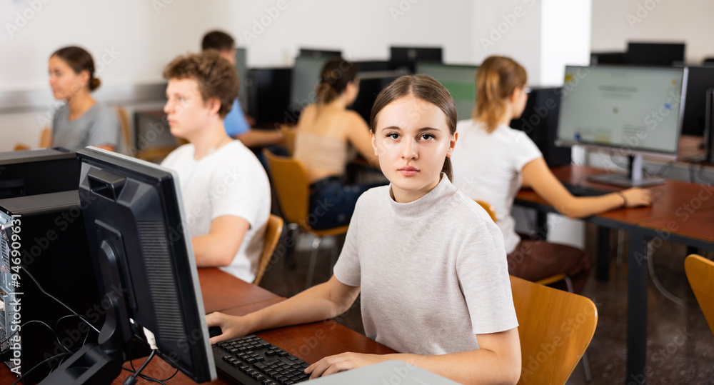 Poster smart female teenager learning computer science while she is using a pc in the computer classroom