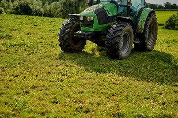 Green tractor, grass field and farming with vehicle for maintenance, agriculture or outdoor...
