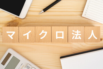 マイクロ法人の文字が入ったブロック、電卓、スマホ、ノート