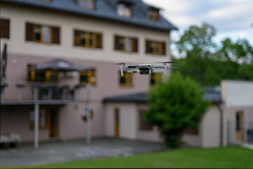 A small drone hovering with a building in the background.