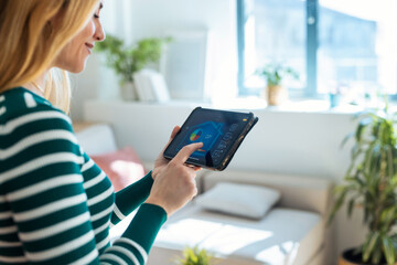 Pretty young woman using the home automation system on digital tablet to regulate the temperature.