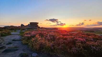 Stunning sunset over Hope Valley from Surprise View, showcasing Millstone Edge and Owler Tor, with vibrant heather in bloom creating a picturesque Peak District landscape.