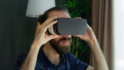 Bearded man wearing a VR headset explores virtual reality experience. Interacting with the virtual...