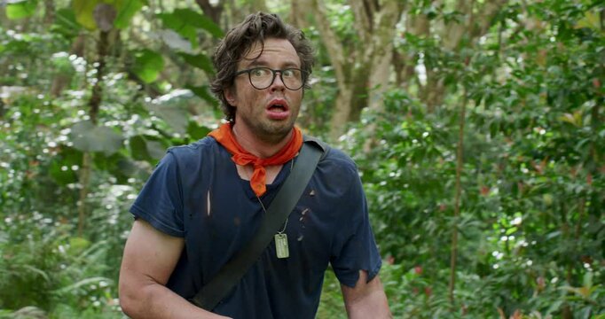 Scared man with toy bow walking through jungle