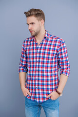 Obraz premium Handsome young man with hairstyle. Trendy male fashion. Male casual style. Skin care and men beauty concept. Caucasian millennial guy. Man in checkered shirt isolated on grey. Male charm